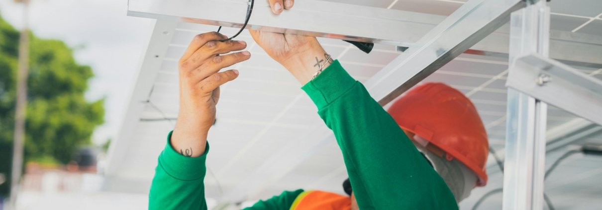 An electrician working on some cables under a roof