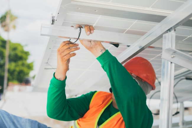 An electrician working on some cables under a roof