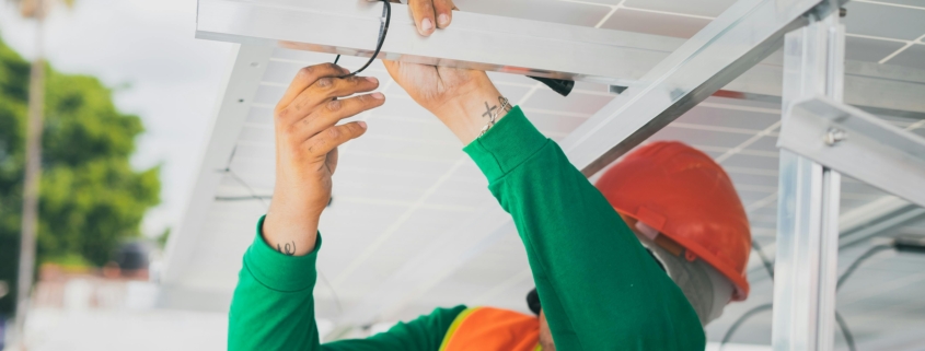 An electrician working on some cables under a roof