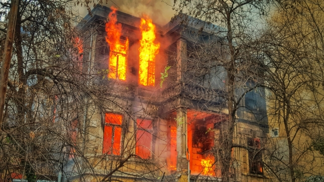 A fire burning in a house behind some trees