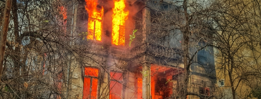 A fire burning in a house behind some trees