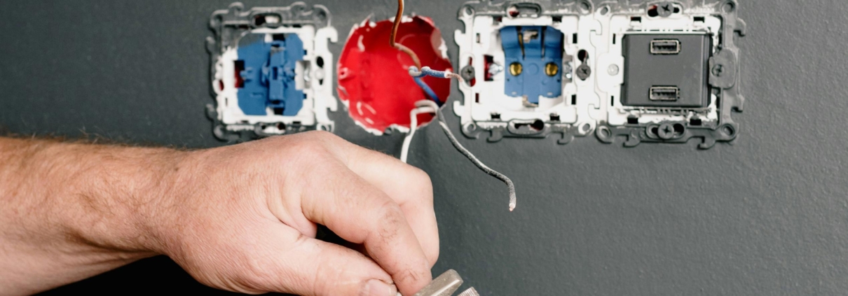 Four plug sockets with wires hanging out, being worked on by an electrician