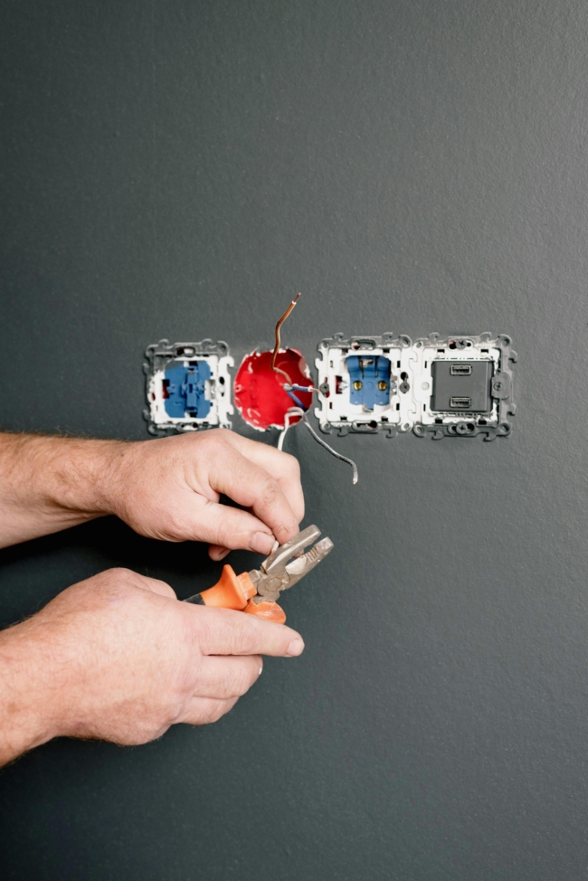 Four plug sockets with wires hanging out, being worked on by an electrician