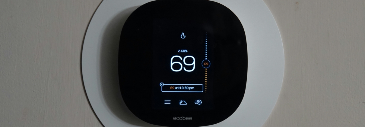 A black smart thermostat against a white wall