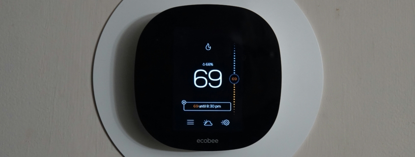 A black smart thermostat against a white wall