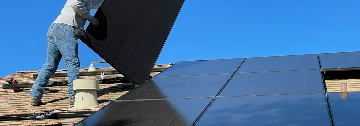 A man installing solar panels on a roof