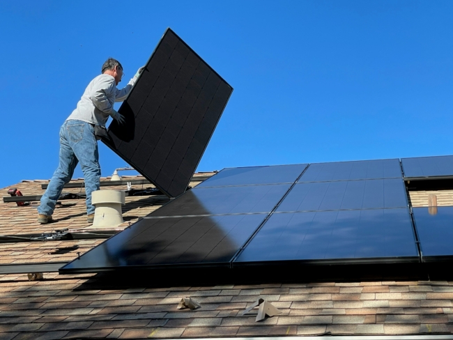 A man installing solar panels on a roof