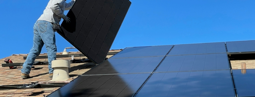 A man installing solar panels on a roof