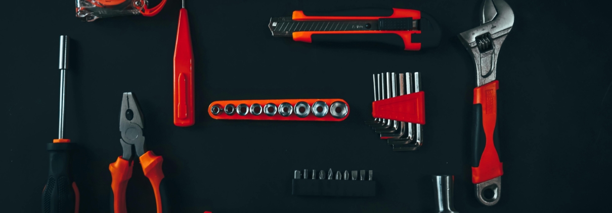 a set of red tools on a black worktop, including a set of pliers, a wrench, a hammer etc.