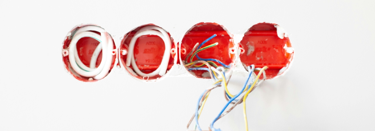 Four holes in a white wall with various wires hanging out during installation